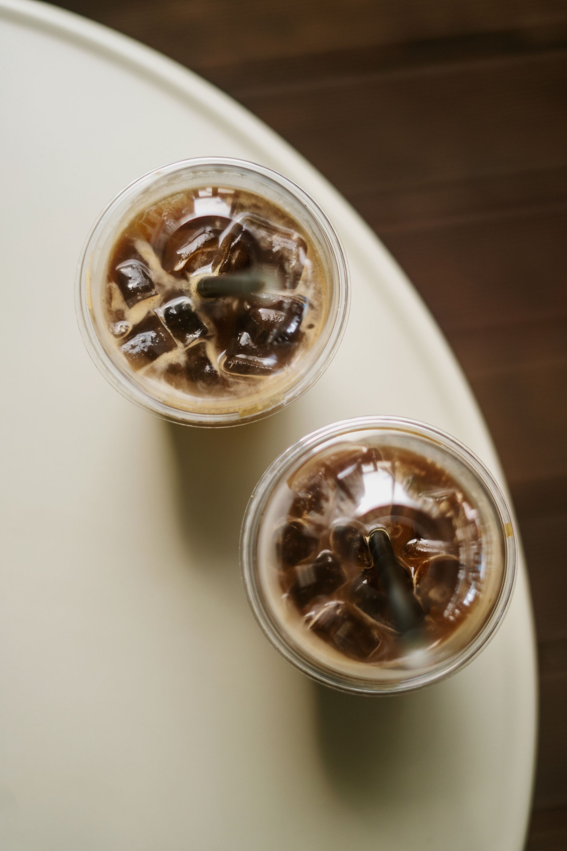 Two refreshing iced coffee drinks with ice cubes viewed from above on a light table.